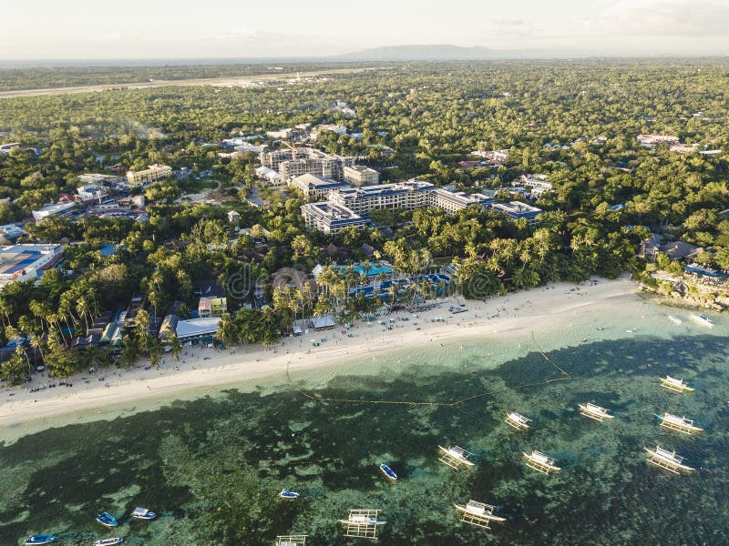 Sunset over Alona Beach in Panglao, Bohol with silhouettes of tourists and palm trees